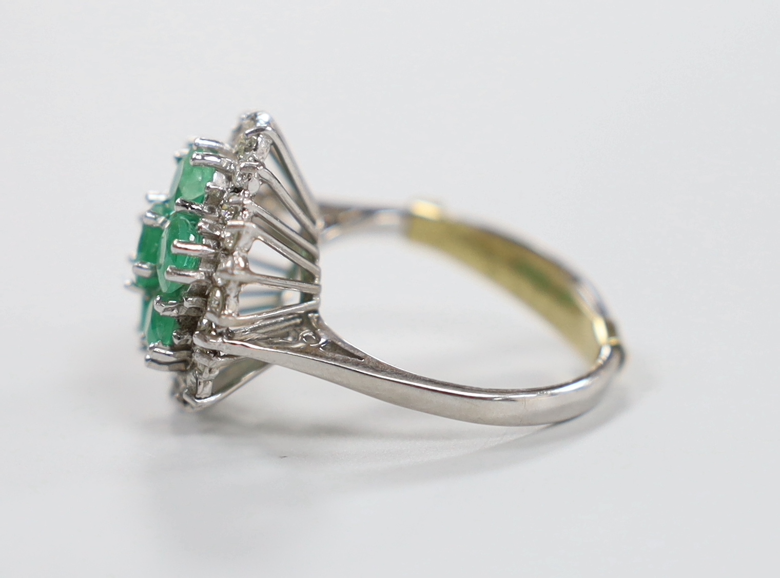 A modern 18ct white gold, emerald and diamond cluster set dress ring, size P/Q, gross weight 7.8 grams.